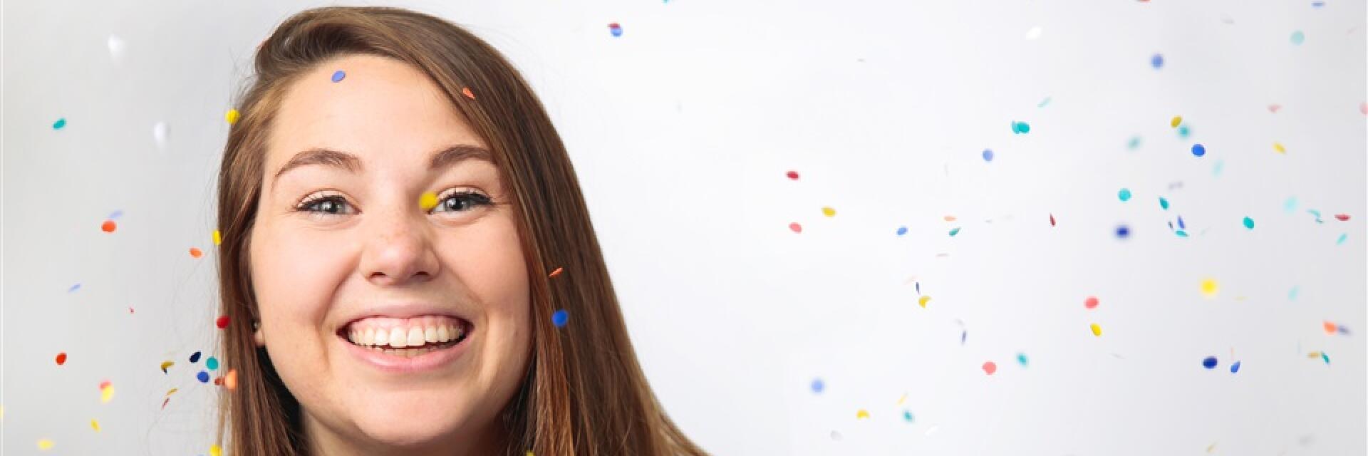 Confetti in the air around a woman with a big smile.